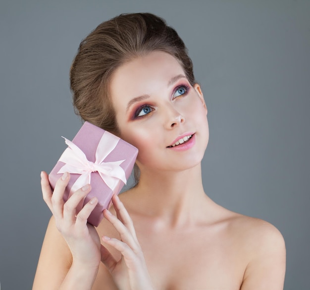 Modèle de jeune femme avec boîte-cadeau rose