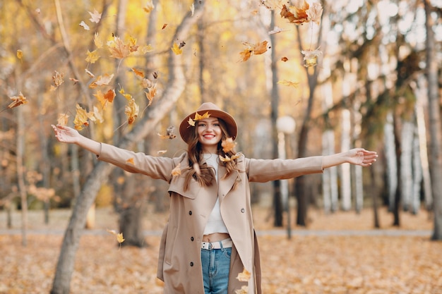 Modèle de jeune femme dans le parc d'automne avec des feuilles d'érable à feuillage jaune. Mode de la saison d'automne.