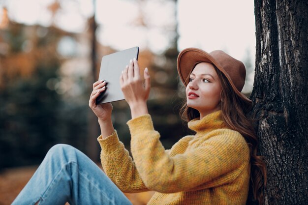 Modèle de jeune femme dans le parc d'automne avec des feuilles d'érable à feuillage jaune. Mode de la saison d'automne.