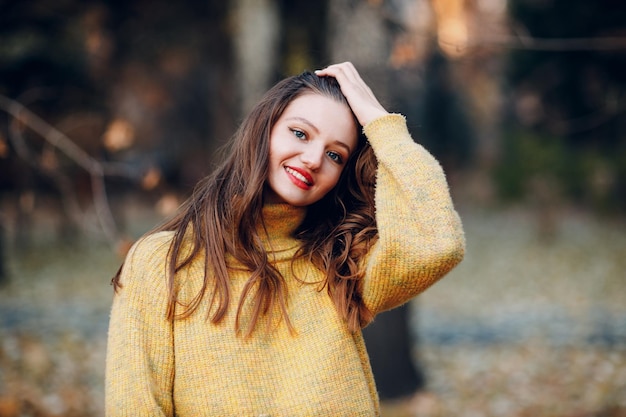 Modèle de jeune femme dans un parc d'automne avec des feuilles d'érable à feuillage jaune Mode de saison d'automne