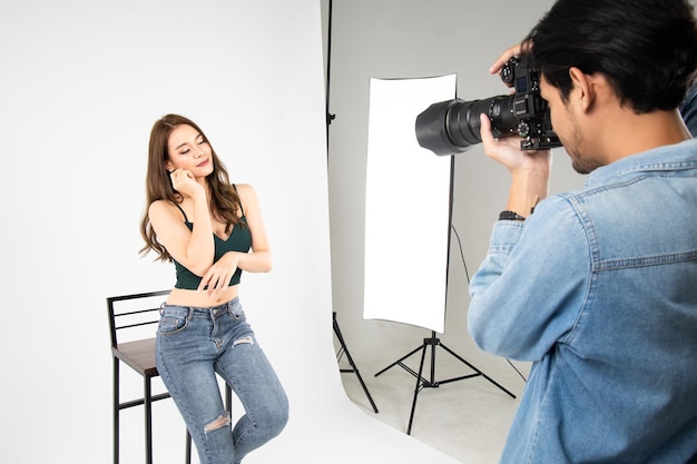 Modèle jeune femme posant pour une photo prise avec un photographe professionnel en studio sur le concept de mode Photographe et modèle Jeune homme photographiant un mannequin