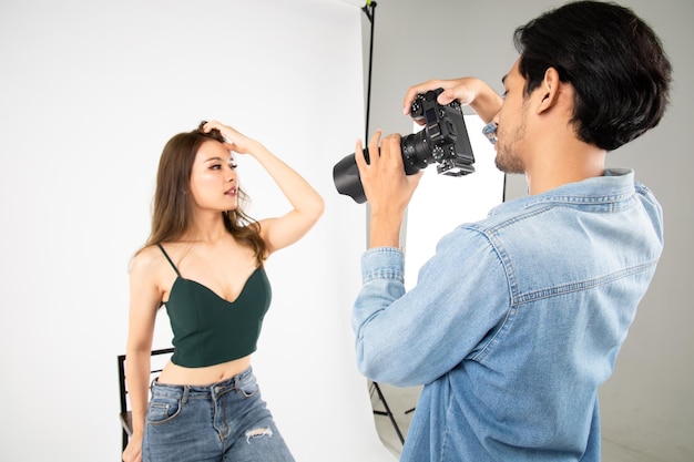 Modèle jeune femme posant pour une photo prise avec un photographe professionnel en studio sur le concept de mode Photographe et modèle Jeune homme photographiant un mannequin