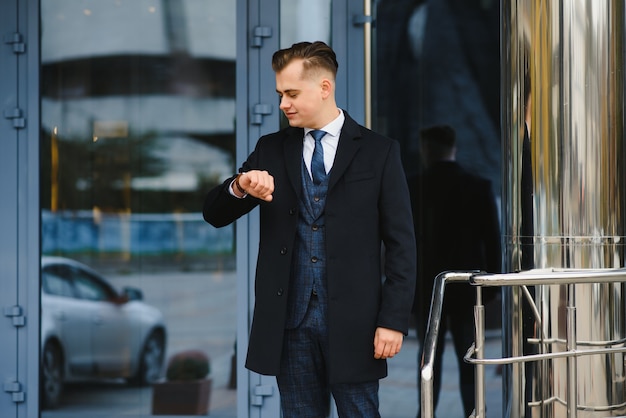 Modèle de jeune homme d'affaires beau confiant élégant en vêtements de costume marchant dans la rue.