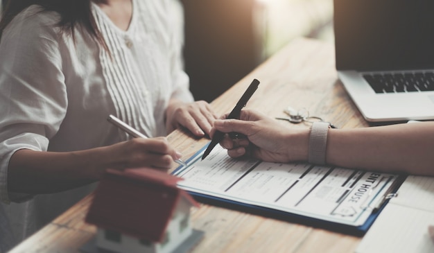 Modèle de maison avec agent et client discutant d'un contrat d'achat, d'assurance ou de prêt d'un bien immobilier ou d'une propriété.