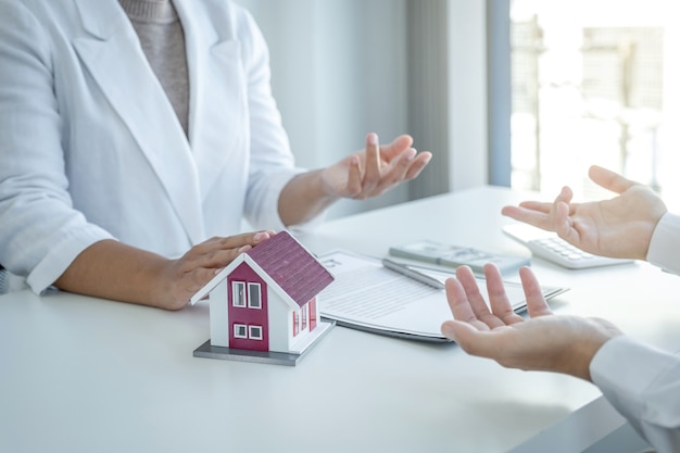 Modèle de maison. L'agent immobilier explique le contrat commercial à la femme acheteuse.