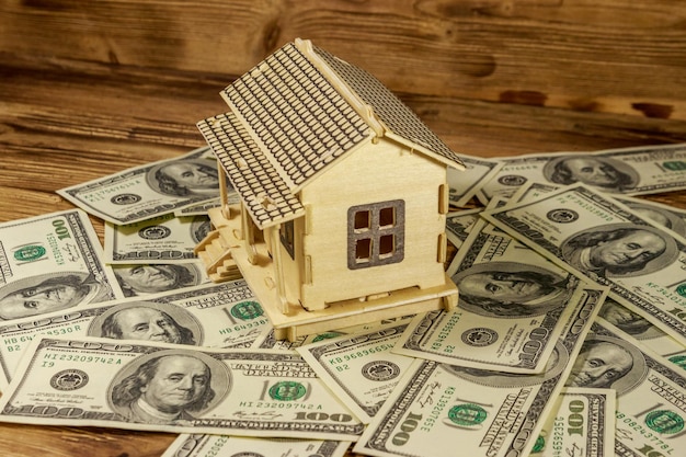 Modèle de maison et billets de cent dollars américains sur fond de bois Investissement immobilier prêt hypothécaire maison concept immobilier