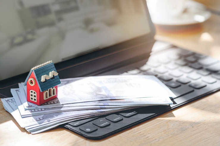 Photo modèle de maison en bois et billet de banque sur le clavier de la tablette.