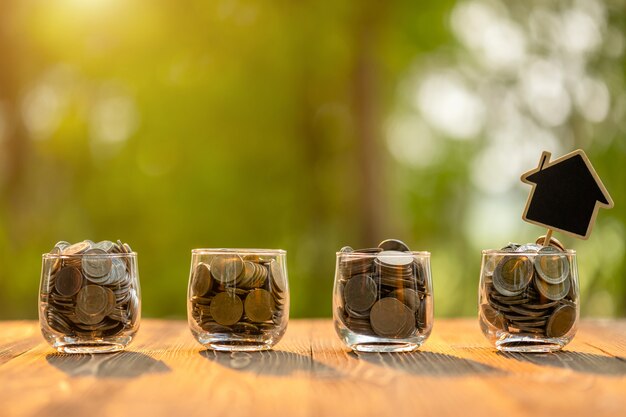 Modèle de maison en bois et pièce en pot transparent sur table en bois. Économies d'argent pour le concept de maison