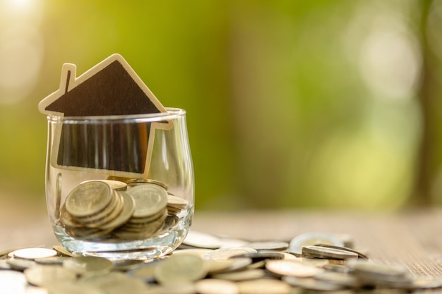 Modèle de maison en bois et pile de pièces sur table en bois. Économies d'argent pour le concept de maison