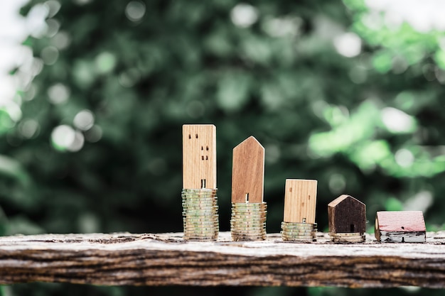 Modèle de maison en bois et rangée de pièces de monnaie sur la table en bois avec backgroud nature lumière.