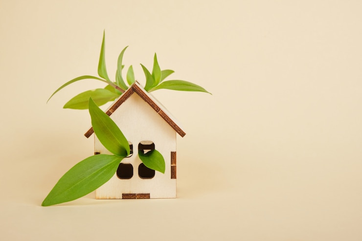 Photo modèle d'une maison sur fond beige, concept de maison écologique, feuilles vertes et espace de copie de maison de jouet