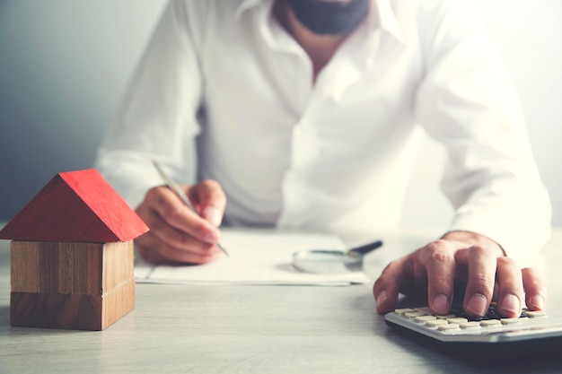 Modèle de maison de main d'homme avec calculatrice et document