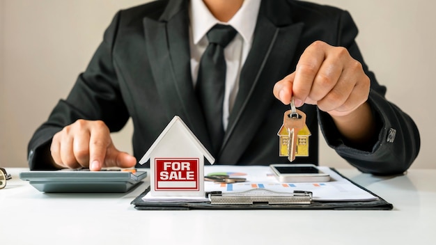 Modèle de maison mis sur les papiers de prêt immobilier et homme d'affaires détenant les clés de la maison concept financier Hypothèque et immobilier