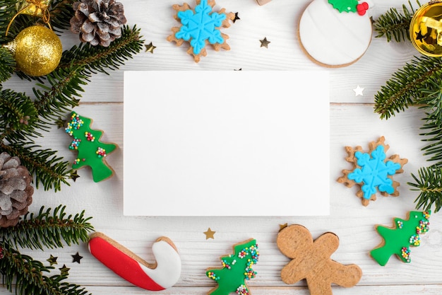 Modèle de maquette de carte de noël x avec des biscuits de pain d'épice de noël brindilles de sapin sur bois blanc