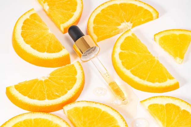 Photo modèle de marque de bouteille de verre à goutte-à-goutte pipette cosmétique arrière-plan à la mode avec des tranches d'oranges concept de cosmétiques biologiques et de beauté lumière solaire dure vue supérieure