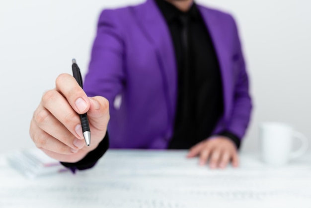 Modèle masculin en costume violet assis à une table blanche et pointant avec un stylo sur un message important Monsieur montrant une annonce critique Tasse à café sur le pont