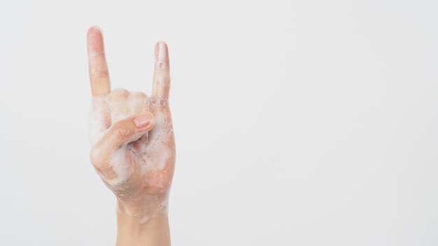 Modèle masculin fait signe de main de cornes de roche ou du diable avec du savon mousse