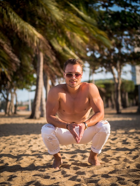 Modèle masculin sur la plage au coucher du soleil