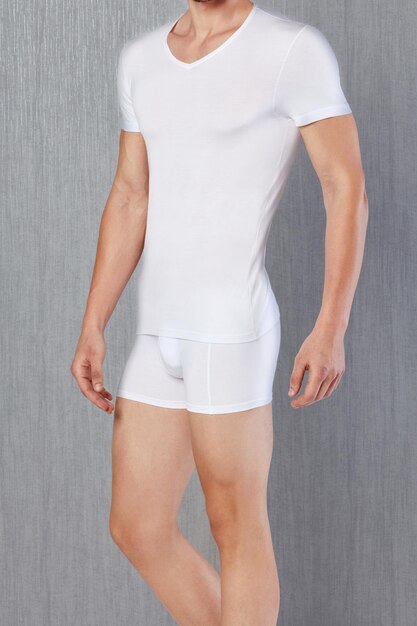 Modèle masculin portant un t-shirt blanc et une culotte devant un fond gris. Sous-vêtements pour hommes.