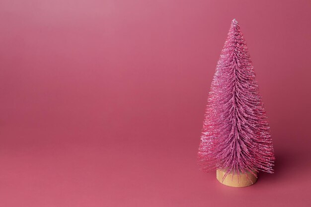 Modèle miniature pin d'hiver avec brillant est décoration d'accessoires pour créer une atmosphère Noël décor de Noël sapin de Noël sur fond rose Espace de copie