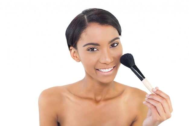 Modèle naturel souriant à l&#39;aide de la brosse blusher