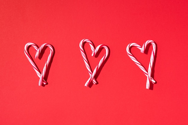 Modèle de Noël de la canne en bonbon avec forme de coeur sur fond rouge