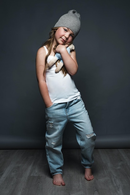 Modèle de petite fille posant professionnellement dans le studio en jeans et un t-shirt blanc