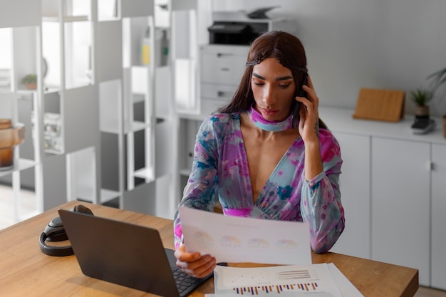 Modèle queer de plan moyen travaillant avec un ordinateur portable