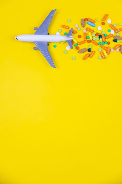 Modèle réduit d'avion avec des pilules multicolores du mal des transports en gros plan sur fond jaune. concept maladie dans travel.selective focus