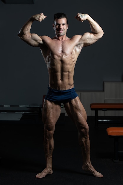 Modèle de remise en forme de bodybuilder posant des doubles biceps après des exercices