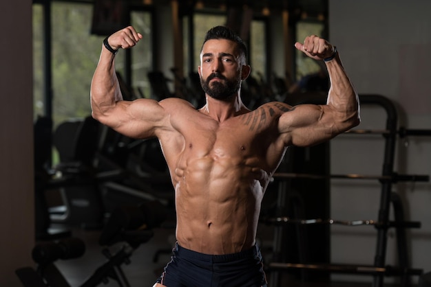 Modèle de remise en forme de bodybuilder posant des doubles biceps après des exercices