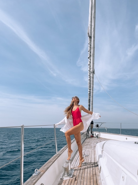 Modèle retourné avec un corps parfait dans un bikini rouge se tient sur son yacht