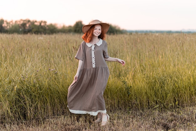 Modèle rousse posant dans un pré au coucher du soleil