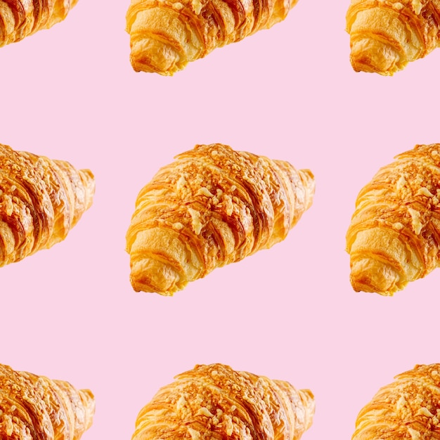 Modèle sans couture à base de croissant frais au fromage isolé sur fond rose