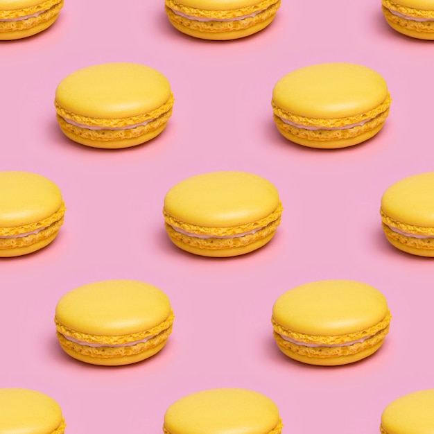 Modèle sans couture avec des biscuits macaron jaunes sur fond rose