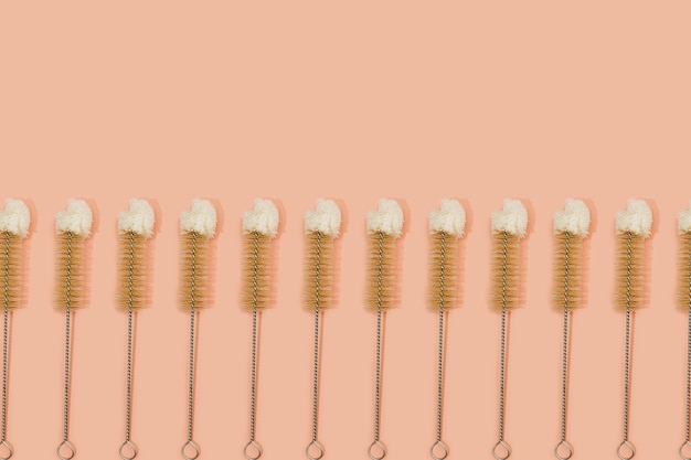 Modèle sans couture fait de brosse à bouteille de nettoyage de noix de coco naturelle et écologique sur fond rose pastel. Mise à plat, vue de dessus. Vie domestique biodégradable durable.