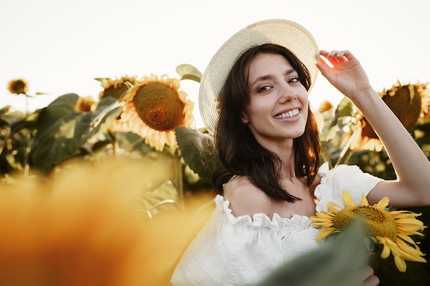 Modèle séduisant de jeune femme posant dans le champ de tournesols