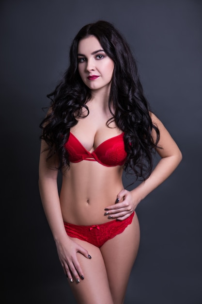 Modèle sexy belle taille plus en lingerie rouge posant sur fond noir