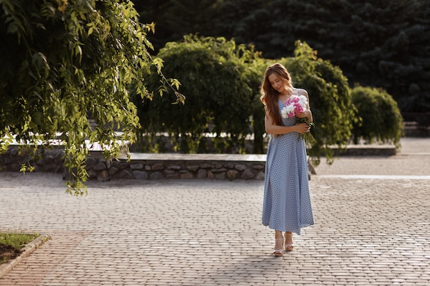 modèle le soir sur une promenade d'été. fille avec un bouquet de fleurs.