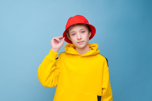 Modèle de style de ville de rappeur tirant un mec heureux hipster en sweat-shirt jaune et chapeau rouge isolé bleu ba...