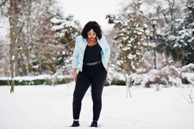 Modèle de taille plus afro-américain élégant avec téléphone portable à portée de main le jour de neige d'hiver