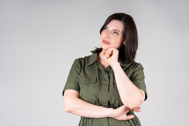 Modèle de taille plus pensif dans des vêtements décontractés grosse femme sur fond gris corps féminin en surpoids