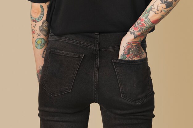 Modèle avec tatouage en T-shirt noir et jeans