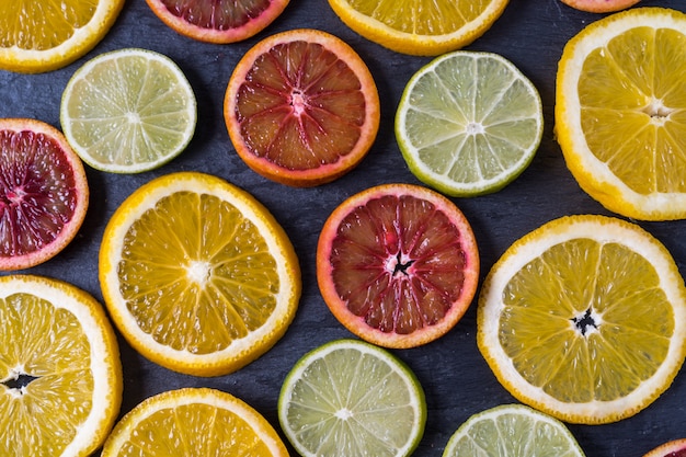 Modèle avec des tranches fraîches d&#39;agrumes différents - orange jaune et rouge, citron et citron vert. Lay plat.