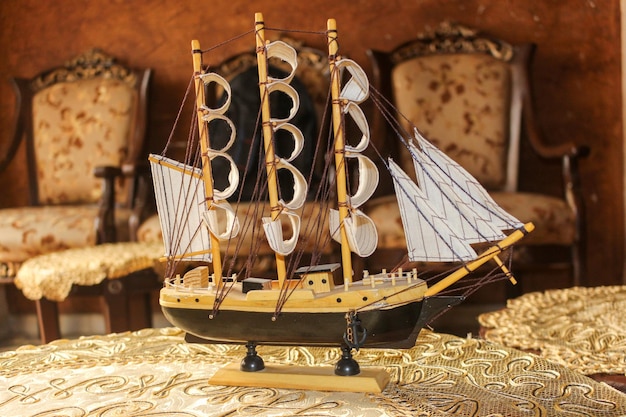 Modèle de voilier en bois affiché dans une maison luxueuse avec des fauteuils et des tables en arrière-plan