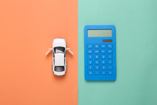 Photo modèle de voiture jouet avec une calculatrice sur fond bleu rose calcul du coût achat de voiture consommation de carburant coûts de service de voiture vue supérieure
