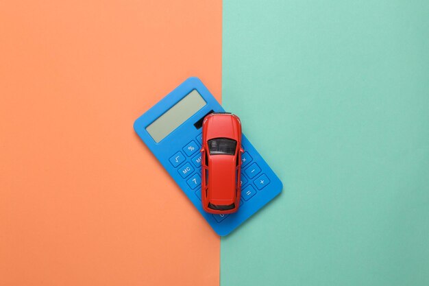 Photo modèle de voiture jouet avec une calculatrice sur fond bleu rose calcul du coût achat de voiture consommation de carburant coûts de service de voiture vue supérieure