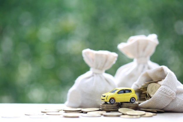 Photo modèle de voiture en miniature sur une pile croissante de pièces d'argent sur un fond vert naturel