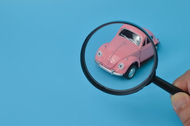 Modèle de voiture rétro rose et loupe Trouver un concept de recherche de voiture et de voiture