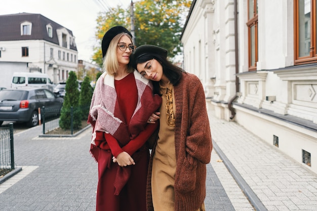 Modèles féminins à la mode sans soucis dans des vêtements et des lunettes d'automne élégants. Jeunes filles de la mode dans des vêtements élégants en laine tissée et des chapeaux sur la rue de la ville urbaine, portrait d'automne.